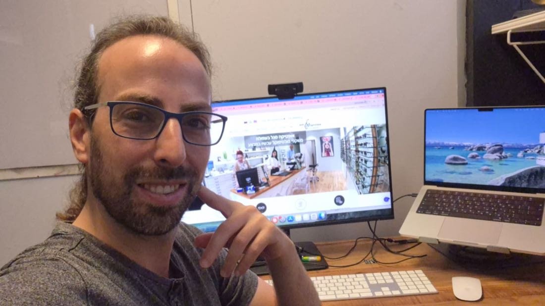 אדם עם משקפיים יושב מול מסך מחשב